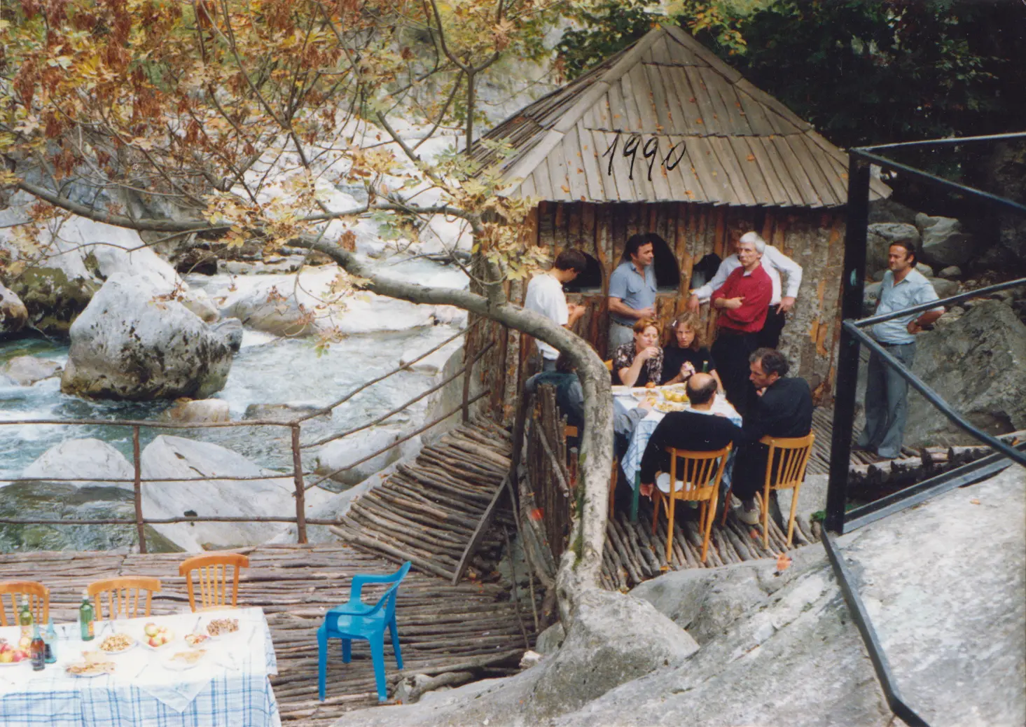 An old photograph of a lunch table beside a mountain river